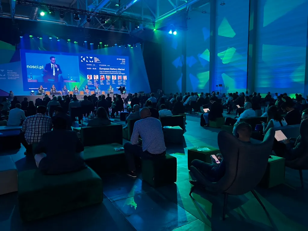 Participants sitting in conference hall with view of stage where panel discussion about European battery market is taking place.