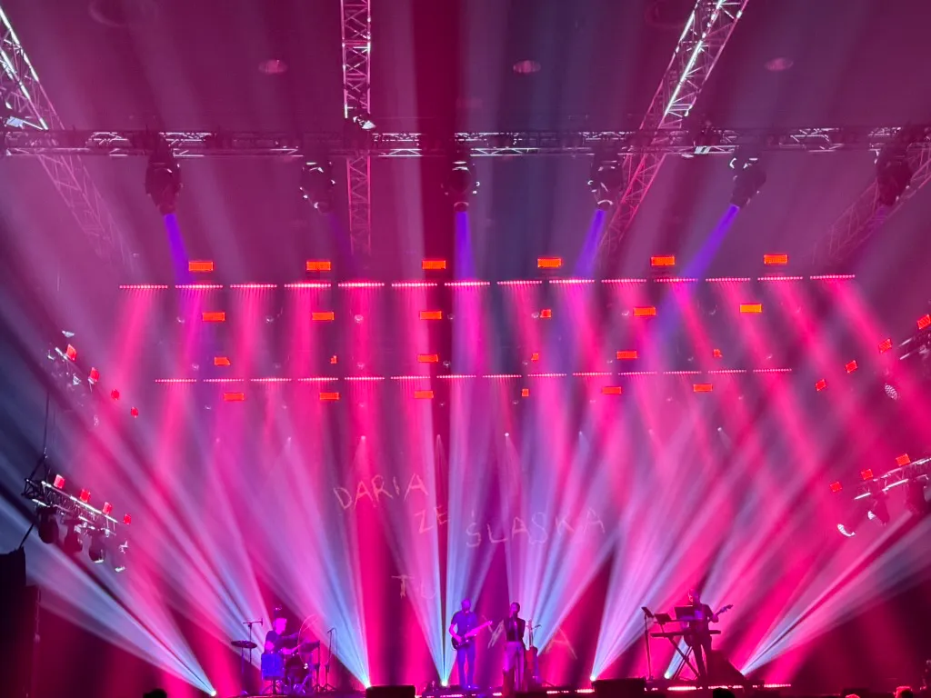 Music band on stage with bright pink and blue lighting.