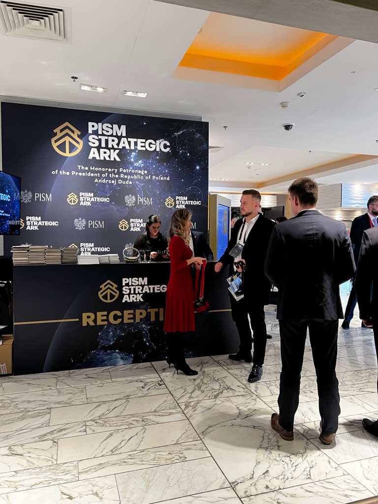 PISM Strategic ARK reception desk with people talking on marble floor.