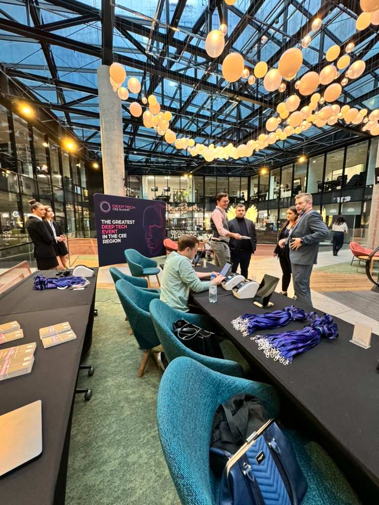 People talking and sitting at tables during technology event in modern office with hanging spherical lamps.