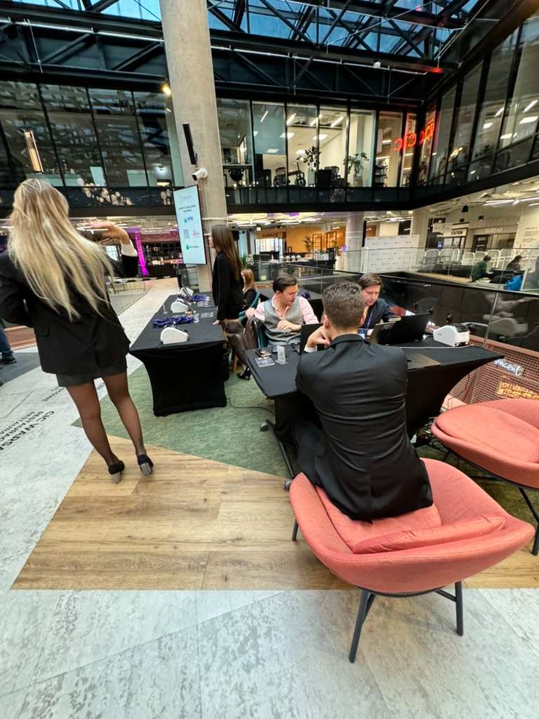 People talking at tables in modern, glass-walled coworking office.